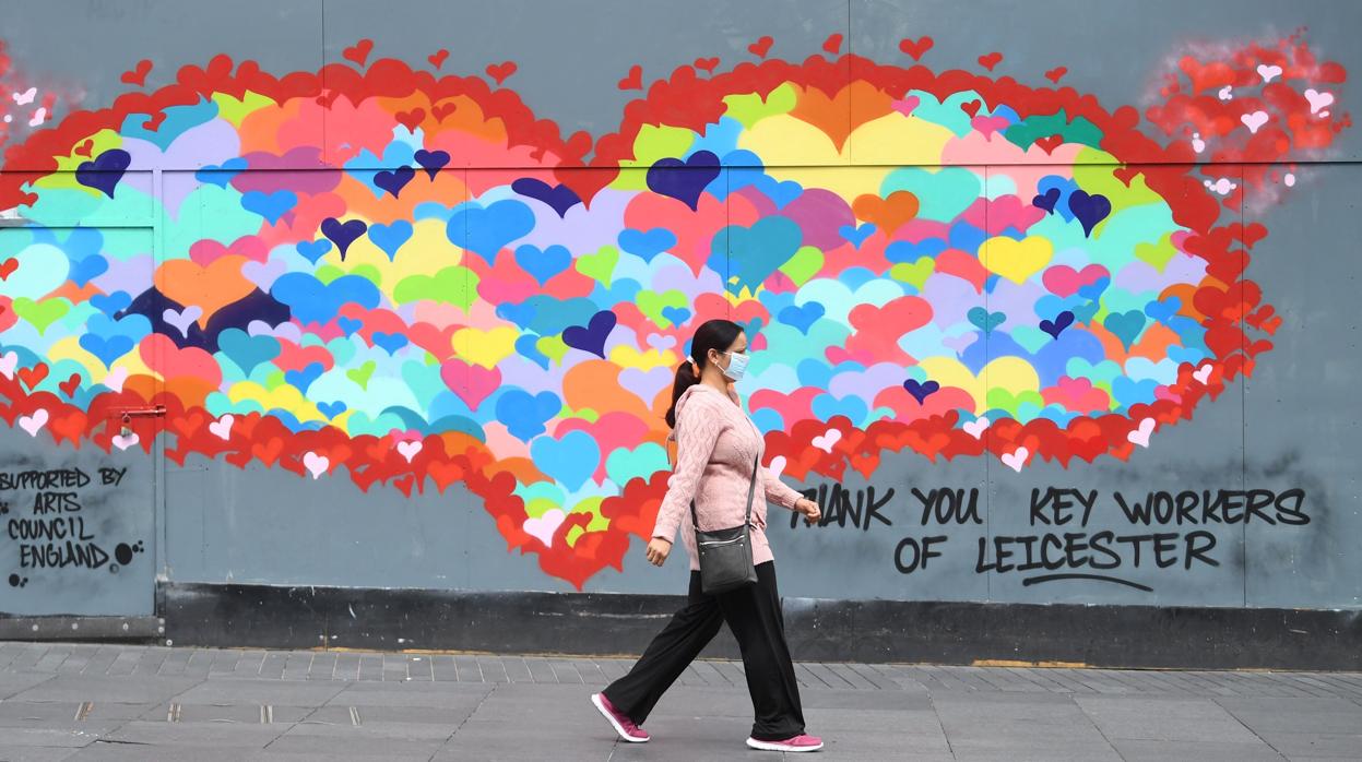 Una mujer con mascarilla pasa delante de un mural en agradecimiento al sector sanitario por su labor en la crisis del coronavirus en Leicester, ciudad que el Gobierno británico ha confinado por el repunte de casos