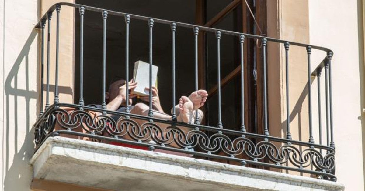 Un hombre lle un libro en su balcón durante el pasado confinamiento