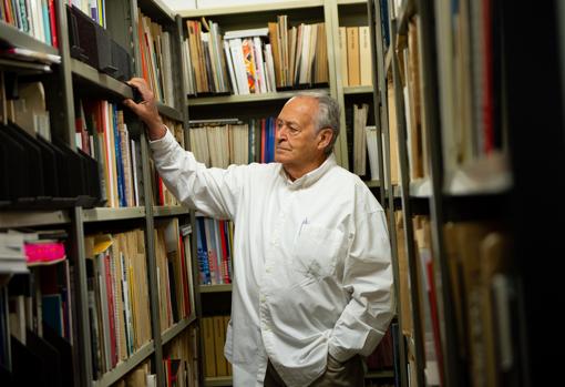 El coleccionista junto a algunos de los cientos de catálogos de arte que guarda