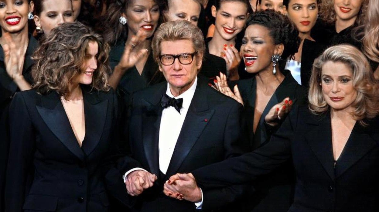 Yves Saint Laurent, en uno de sus desfiles, junto a sus musas Laetitia Casta y Catherine Deneuve