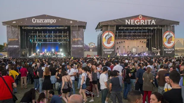 Crowd of music enthusiasts at the Interestelar Sevilla festival, with contemporary bands performing against a backdrop of Sevilla's historic architecture