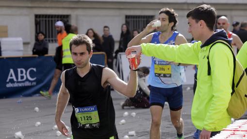 Un maratoniano coge un vaso con agua en un punto de avituallamiento