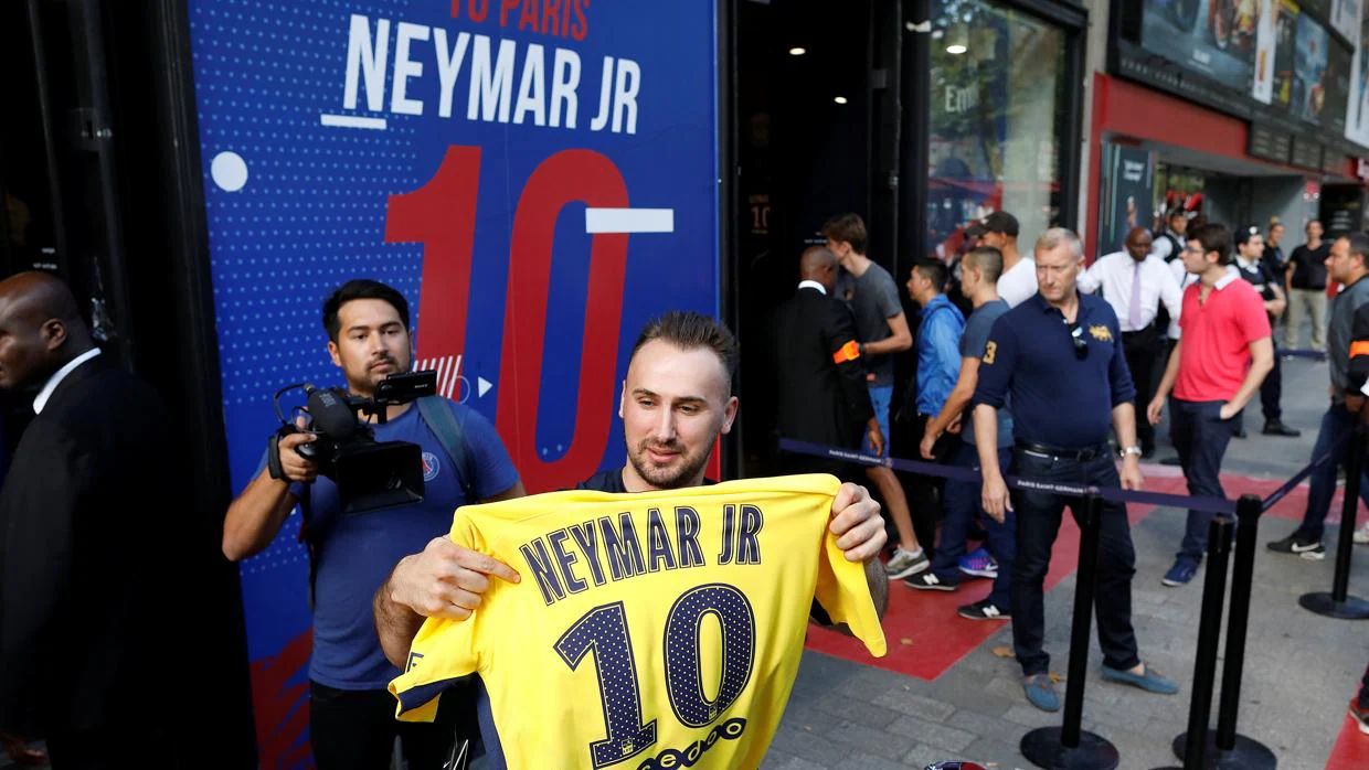 Un aficionado del PSG muestra una camiseta de Neymar recientemente adquirida tras soportar una larga cola