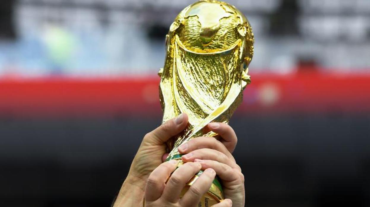 Unos aficionados ingleses sostienen una réplica de la copa del mundo