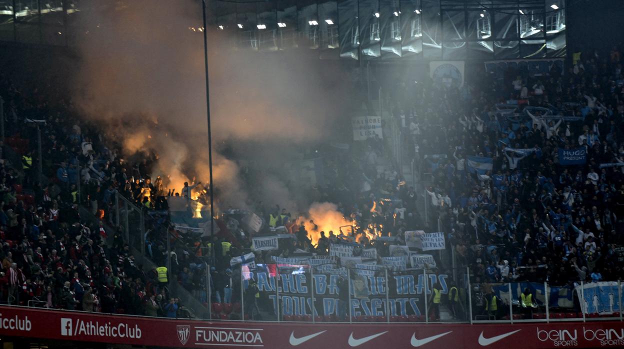 Aficionados del Olympique de Marsella encienden bengalas en la grada durante el partido ante el Athletic de Bilbao