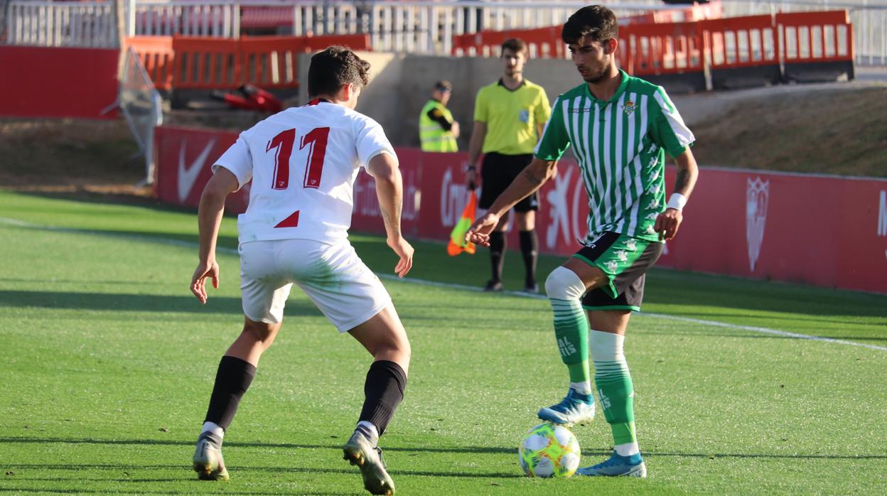 Calderón, del Betis Deportivo, pisa la pelota ante el sevillista Isaac