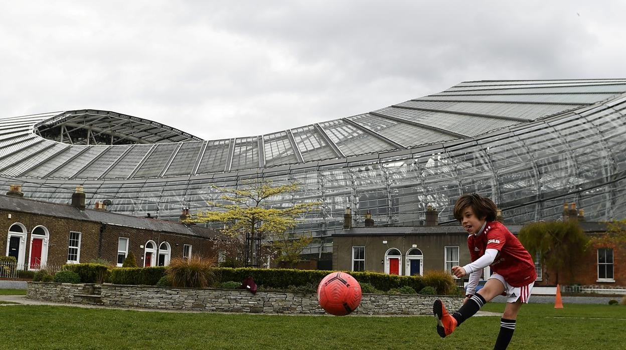 Un niño juega al fútbol en los aledaños del Dublín Arena