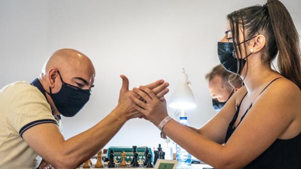 Claudia 'escribe' en la mano de José Manuel, jugador sordociego, las jugadas de su rival en un torneo de ajedrez, en San Fernando