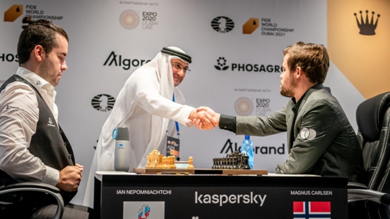 Ian Nepomniachtchi y Magnus Carlsen, que saluda al árbitro, en el comienzo de la primera partida del Mundial de Ajedrez