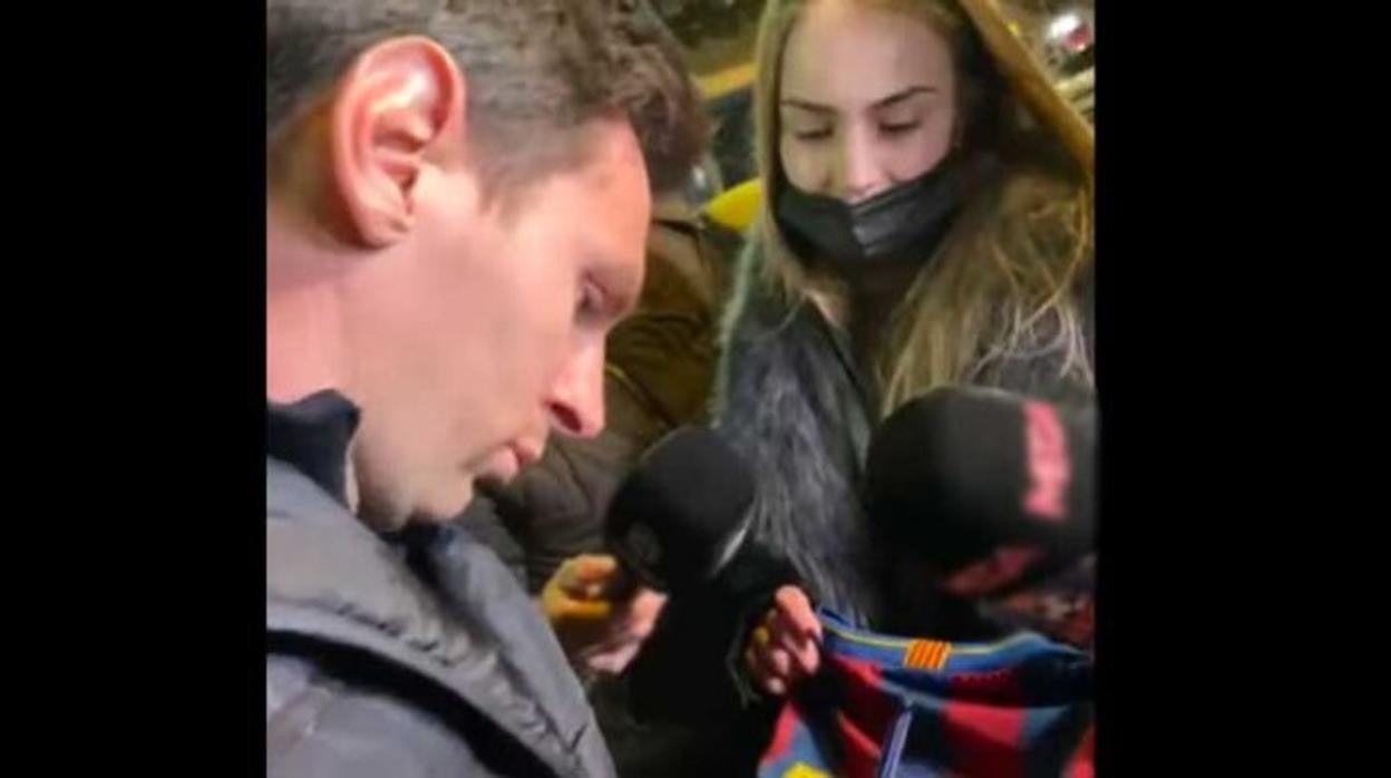 Messi firma una camiseta a la salida de la cena