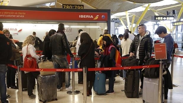 Varias personas esperan ser atendidas en el mostrador de Iberia de la T-4 del aeropuerto Adolfo Suárez Madrid-Barajas, donde los doce vuelos previstos con destino Bruselas han sido cancelados