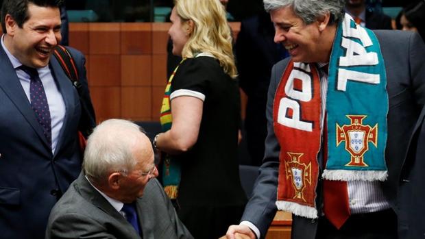 El ministro portugués de Finanzas estrecha la mano de Schäuble con la bufanda de la selección portuguesa