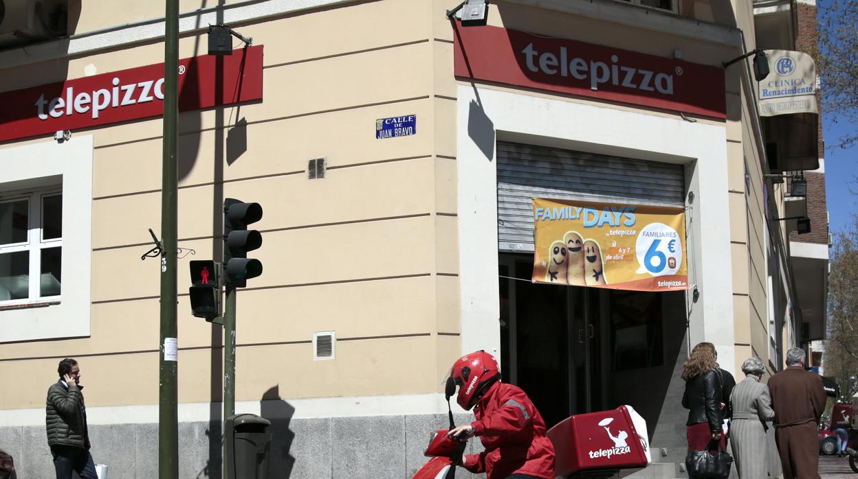 Un repartidor de Telepizza pasa enfrente de un local de Tellepizza en Madrid