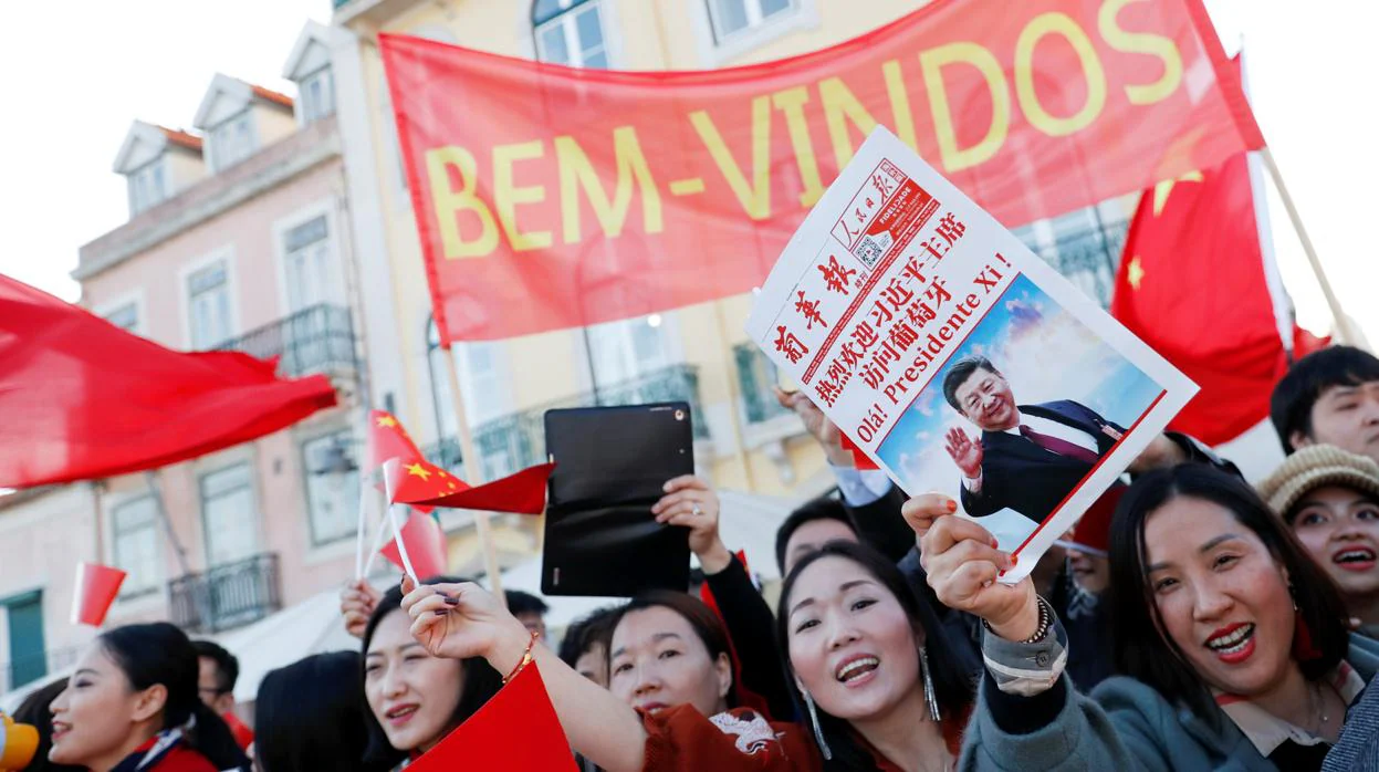 Un grupo de jóvenes saluda a la comitiva de Xi Jinping en las calles de Lisboa