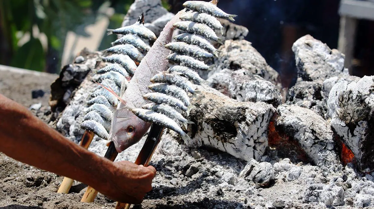 Un espetero preprara unas sardinas en un chiringuito de Málaga