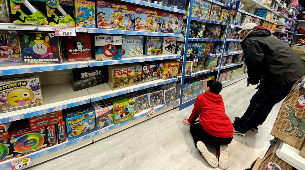 Un niño mira productos junto a su padre en la sección de juguetes infantiles de un centro comercial de Madrid