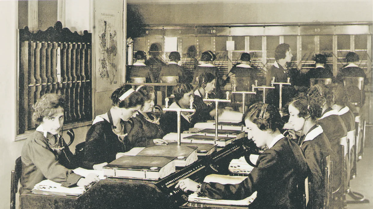 En la imagen superior, tomada en 1927, un grupo de telefonistas trabaja en la mesa de información de la central de Telefónica en la madrileña calle de Hortaleza