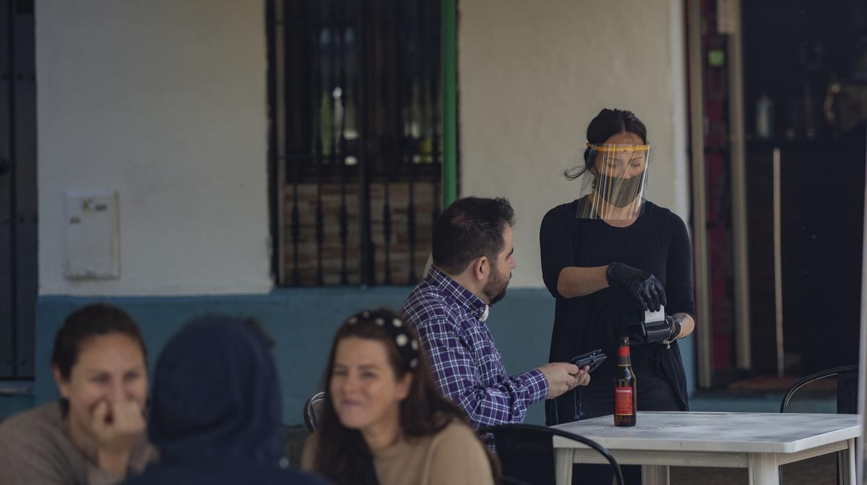 Una camarera sirve una mesa en una terraza sde Sevilla