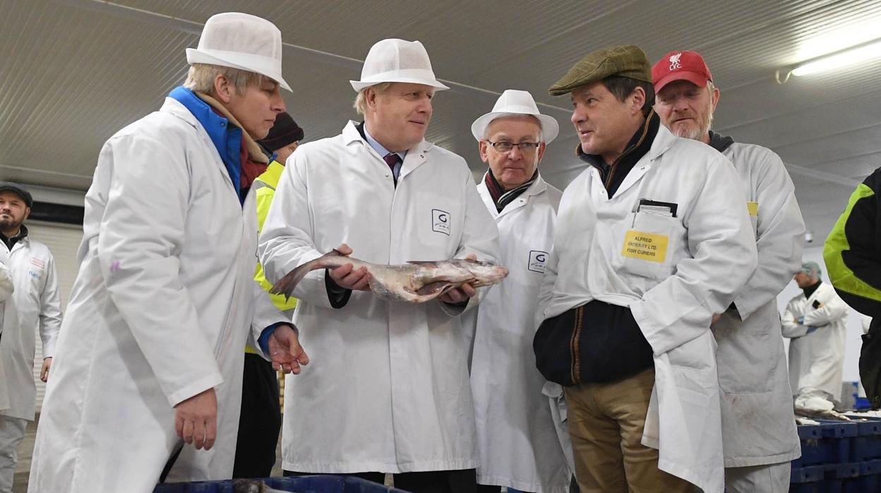 El primer ministro británico, Boris Johnson (centro de la imagen sosteniendo un pescado) junto a representantes de la flota pesquera británica