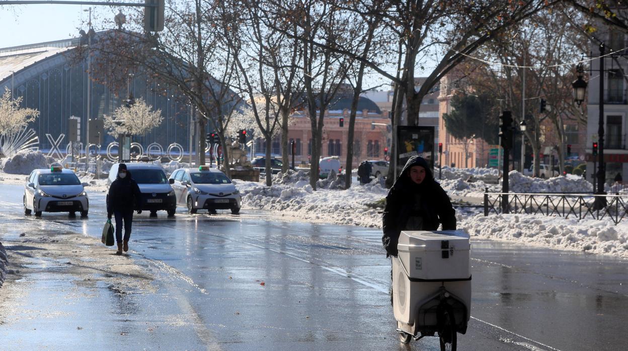 Pocos vehículos y algún transeúnte en la calzada en las inmediaciones de la Estación de Atocha, este lunes en Madrid, tras el temporal de nieve causado por la tormenta Filomena