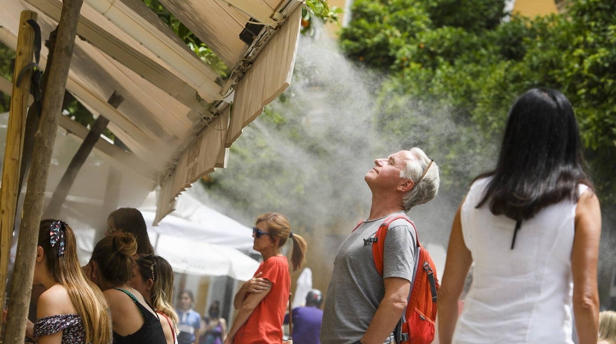 Turistas se refrescan con los vaporizadores de un bar en el centro de Sevilla