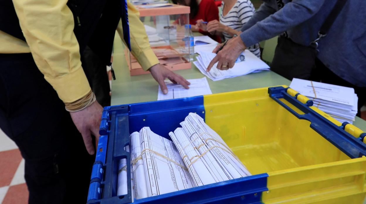 Un funcionario de correos hace entrega, a la presidenta de una mesa del colegio electoral, de votos emitidos por correo