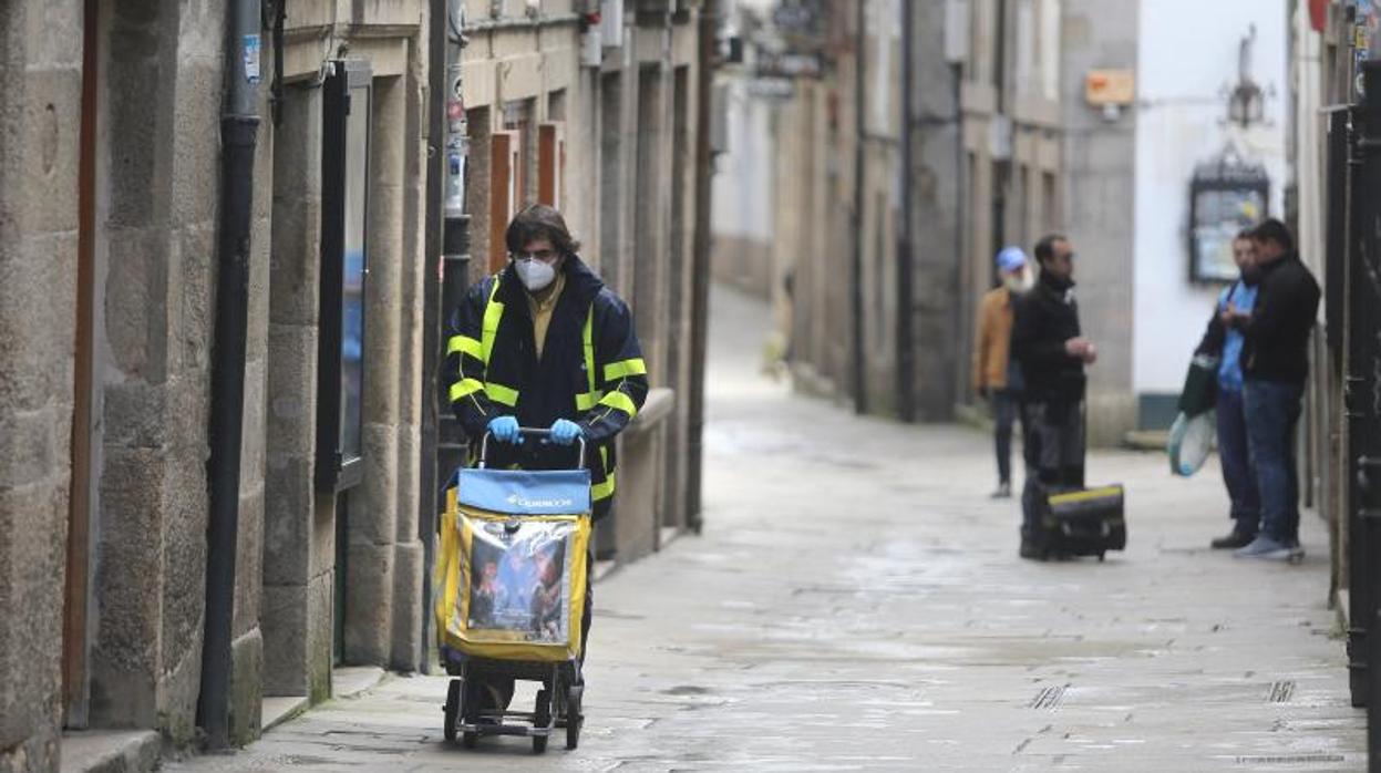 Un empleado de Correos realiza un reparto en Santiago durante la pandemia de coronavirus