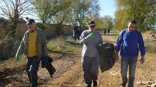 El poeta y sus colaboradores recogen en grandes bolsas la basura del camino