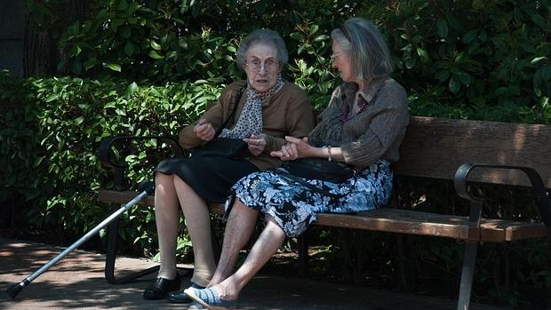 Dos mayores conversan sentadas en un banco