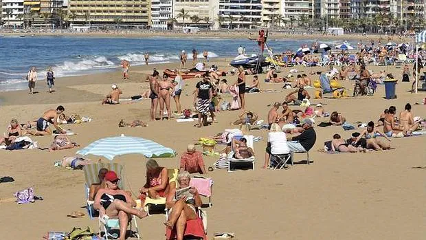 Turistas en toman el sol en la playa de Las Canteras