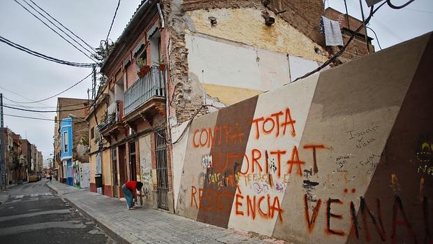 Un hombre realiza una pintada en una de las calles afectadas por la paralización de El Cabanyal