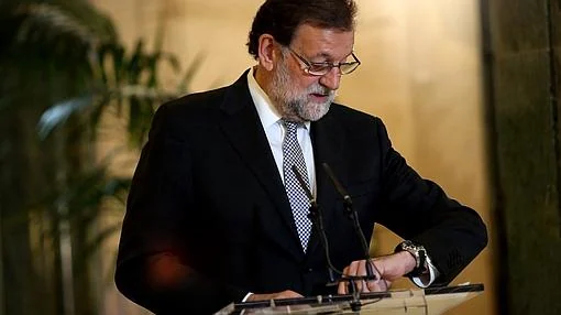 Rajoy mira al reloj antes de una rueda de prensa en el Congreso
