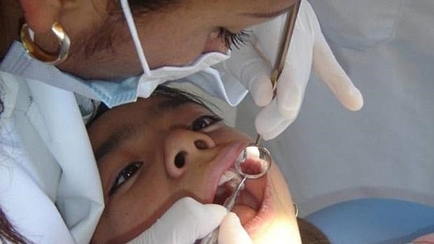 Un dentista revisa la boca de un niño