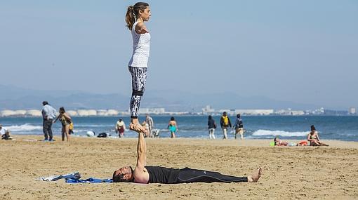 Una pareja practica yoga en la playa de las Arenas