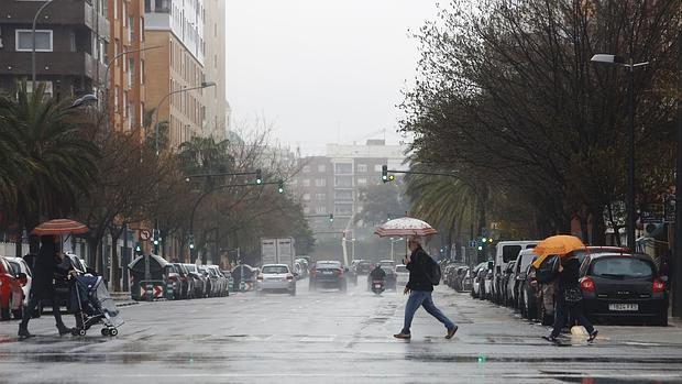 Varias personas se protegen de la lluvia en Valencia