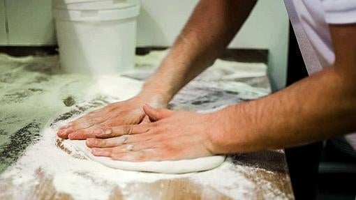 Un cocinero realiza la masa de una pizza