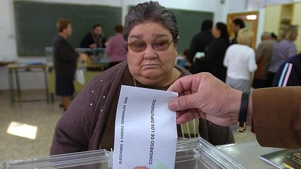 El presidente de una mesa electoral introduce la papeleta de una votante