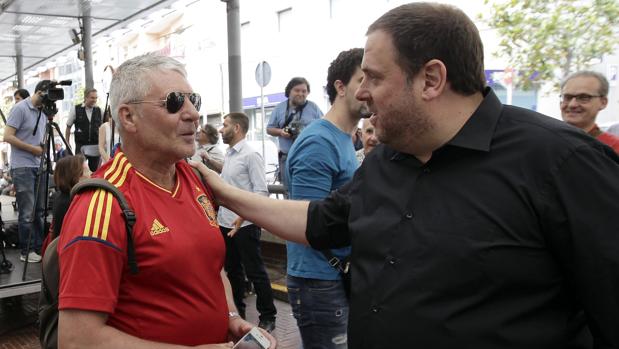 Junqueras, saluda a un hombre vestido con una camiseta de la selección española de fútbol poco antes del mitin