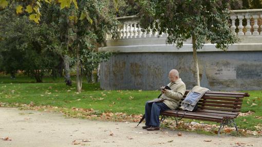 Un anciano descansa en un banco de El Retiro