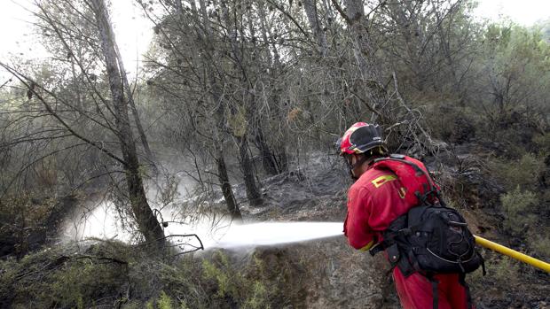 Imagen de un miembro de la UME refresca zonas quemadas en el perímetro del incendio de la Sierra de Espadán