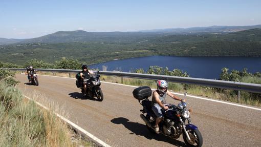 Unos moteros transcurren por la ruta dejando a sus espaldas el lago Sanabria