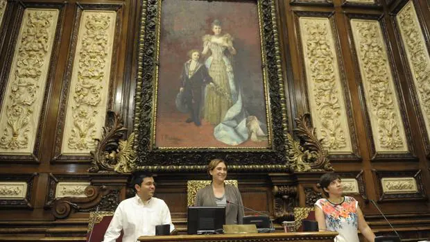 Ada Colau y dos de sus concejales, en el salón de plenos frente a un retrato de la Reina Regente