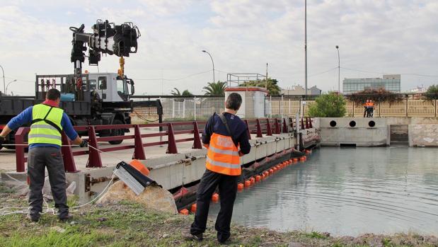 Imagen de unos operarios del puerto de Valencia frente a la barrera anticontaminación