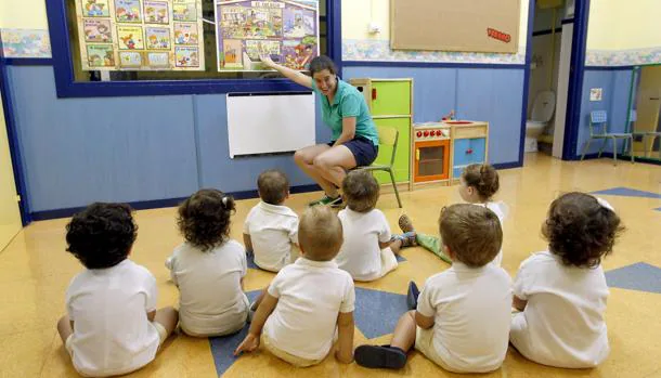 Los pequeños, muy atentos a la explicación de su profesora, en una escuela infantil
