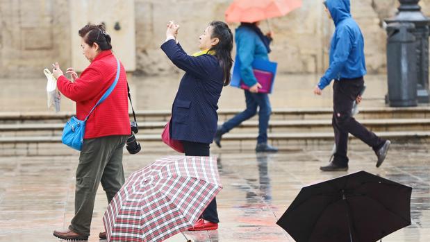 Varias personas se protegen de la lluvia, este martes, en Valencia