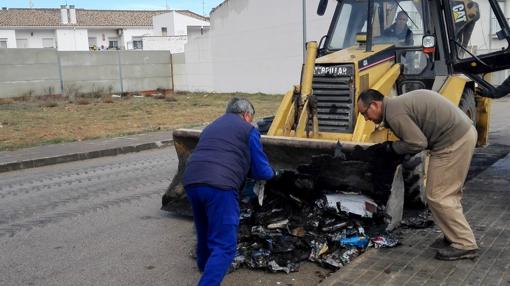 Operarios municipales retiran los restos de un contenedor incendiado