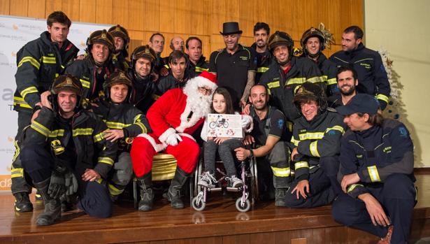 Papa Noel y los bomberos del Ayuntamiento de Madrid posan con una pequeña ingresada en el hospital