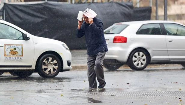 Un hombre se protege de la lluvia en Valencia