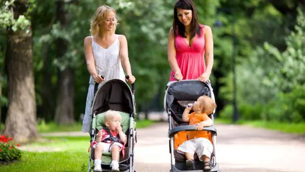 Dos madres pasean juntas con sus bebés en carritos