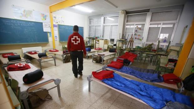 Un voluntario de Cruz Roja en una aula acondicionada como albergue para desalojados por el temporal en Orihuela